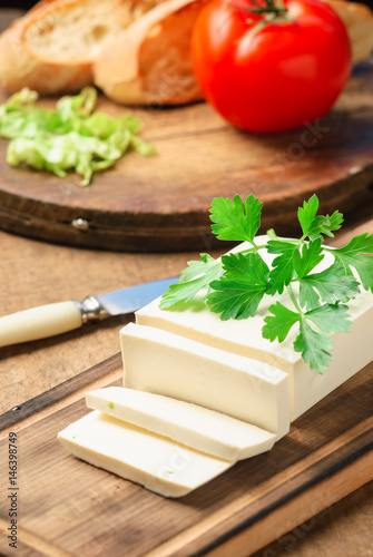 feta cheese on a wooden board decorated with fresh parsley. close up and selective focus