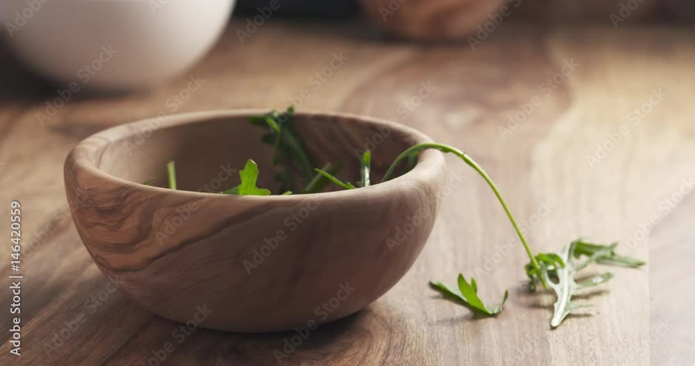 washed arugula leaves falling into the bowl on wooden table, 4k 60fps prores footage washed arugula leaves falling into the bowl on wooden table, 4k 60fps prores footage