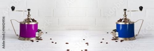 Mechanical coffee mill with coffee beans on white wooden table. Copy space. Wide panoramic image