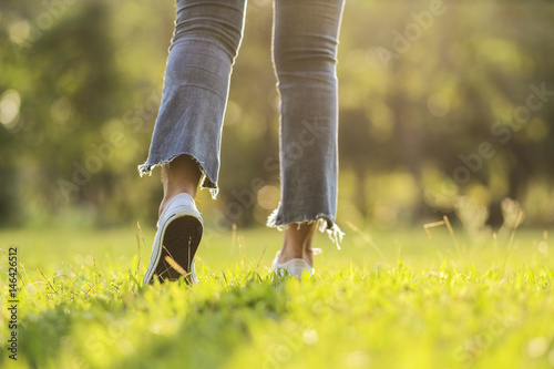 white sneaker jeans walking on green grass with sunset light