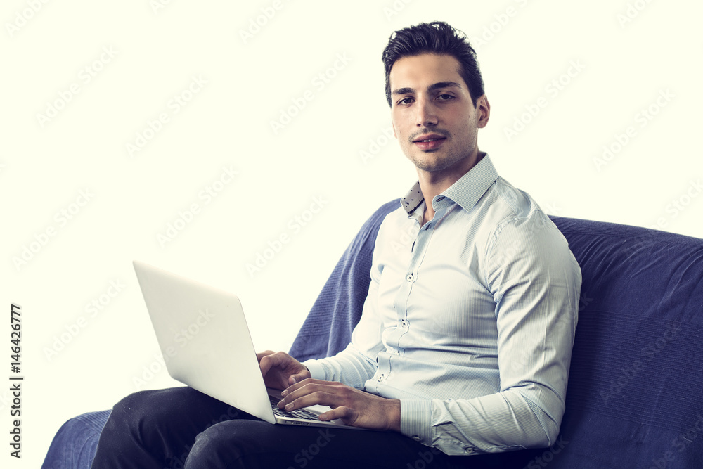 Young attractive man working with computer while sitting on couch, on white background Young attractive man working with computer while sitting on couch, on white background