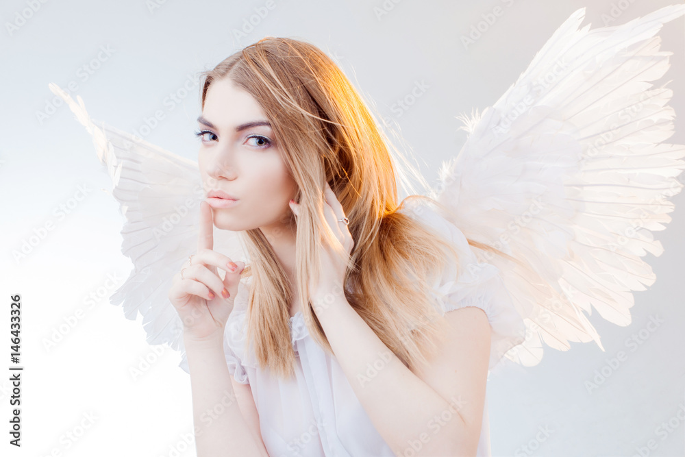 Angel keeps the secret. Young, wonderful blonde girl in the image of an angel with white wings. Angel keeps the secret. Young, wonderful blonde girl in the image of an angel with white wings.