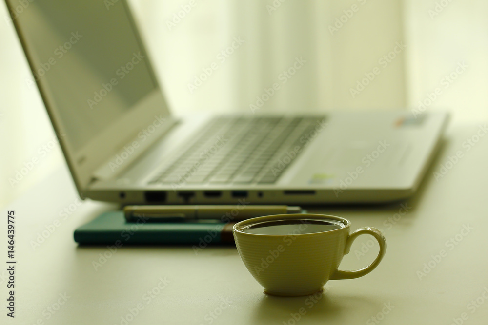 Stock Photo - Coffee and laptop in soft focus setting with dramatic ambient light Stock Photo - Coffee and laptop in soft focus setting with dramatic ambient light