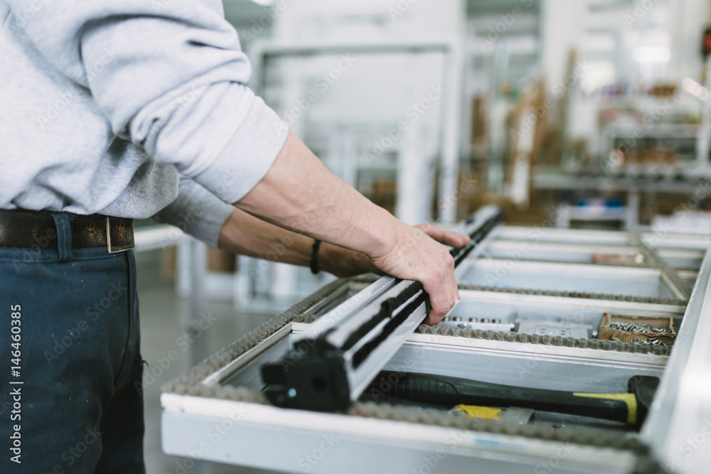 Factory for aluminum and PVC windows and doors production. Manual worker assembling PVC doors and windows. Selective focus. Factory for aluminum and PVC windows and doors production. Manual worker assembling PVC doors and windows. Selective focus.