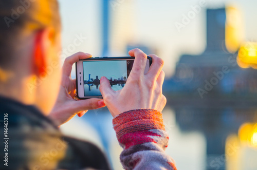 Young woman takes pictures of the city on a smartphone