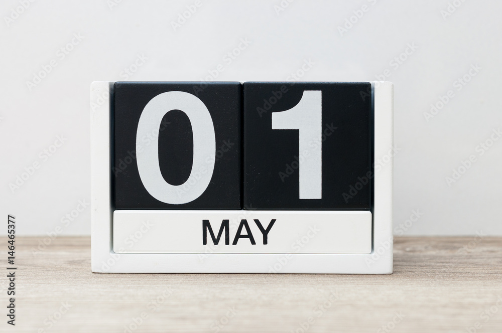 May 1st. Day 1 of month, calendar close-up, at wooden table and white background. Spring time
