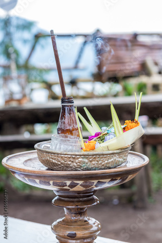 Traditional balinese offerings to gods in Bali with flowers and aromatic sticks. Tropical island Bali, Indonesia. photo