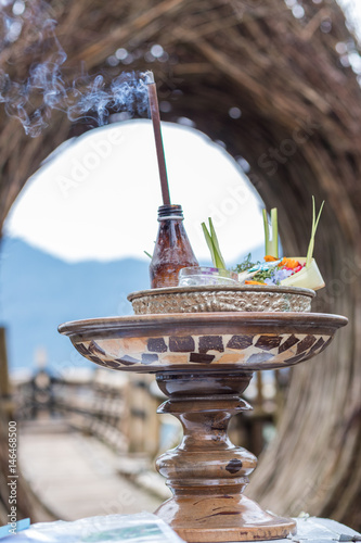 Traditional balinese offerings to gods in Bali with flowers and aromatic sticks. Tropical island Bali, Indonesia. photo