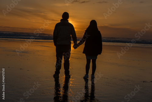 couple holding hands at beach at sunset