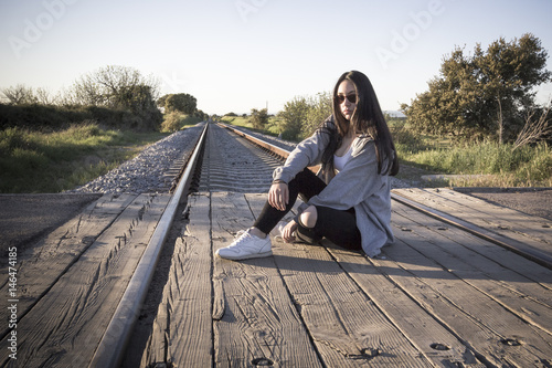 Joven sentada en las vías del tren