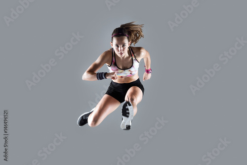 Fototapeta Naklejka Na Ścianę i Meble -  Fit and sporty young woman jumping on white background.