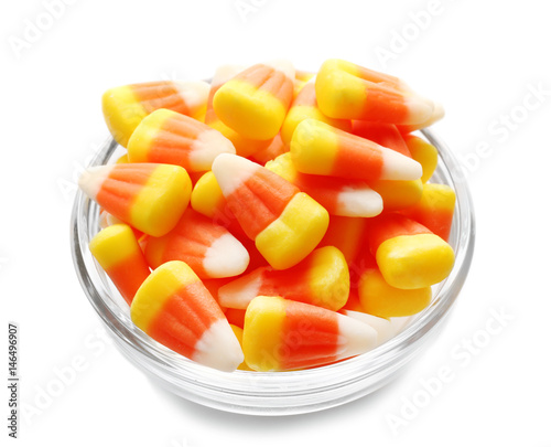 Colorful Halloween candy corns in bowl on white background