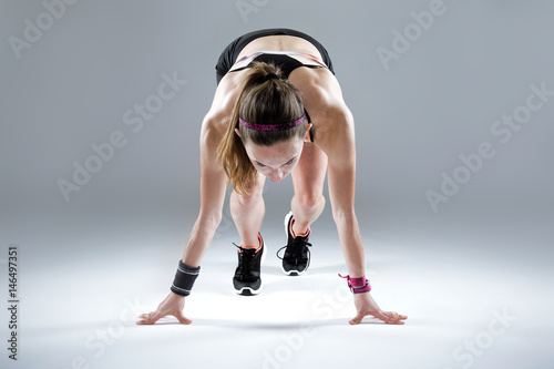 Fit and sporty young woman preparing for a run on white background.