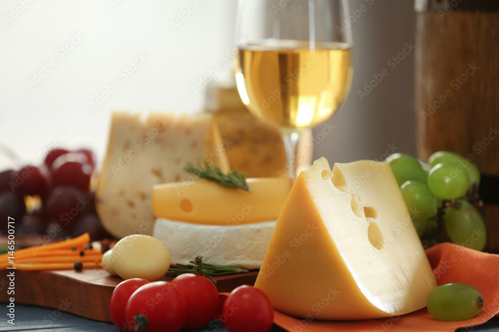 Wooden board with variety of cheese on table Wooden board with variety of cheese on table