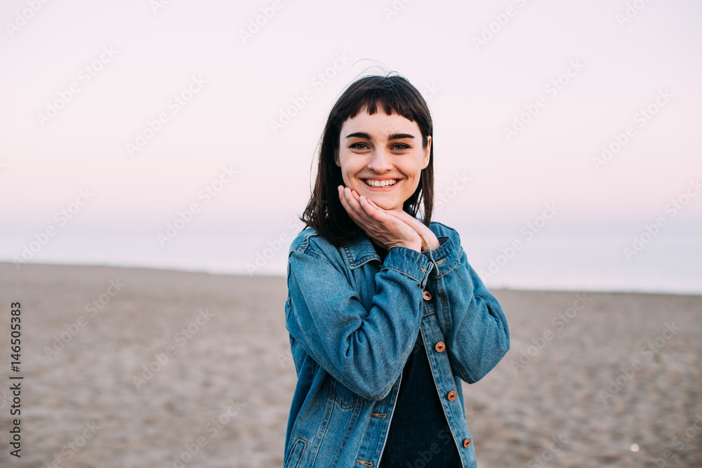 Cute dark haired russian girl poses during photoshoots on the beach with a pink sunset sky in the sand near the sea with the beach all smile filming and photograph portraits. Cute dark haired russian girl poses during photoshoots on the beach with a pink sunset sky in the sand near the sea with the beach all smile filming and photograph portraits.