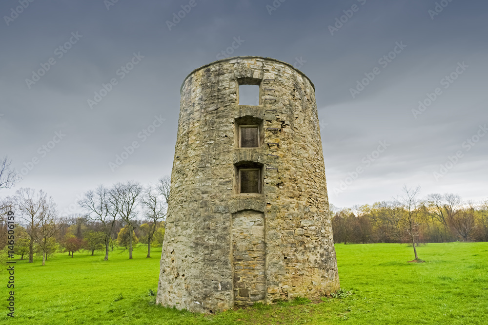 Rustic old brick silo ruin stands tall against a stormy blue sky