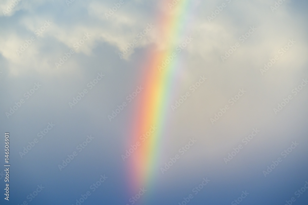 Vibrant rainbow against a misty stormy sky, white fluffy clouds up high Vibrant rainbow against a misty stormy sky, white fluffy clouds up high