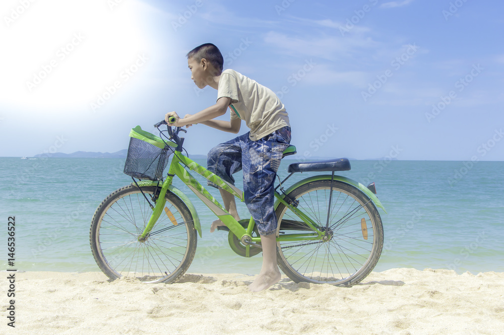 Happy little boy ride bicycle playing on the beach.