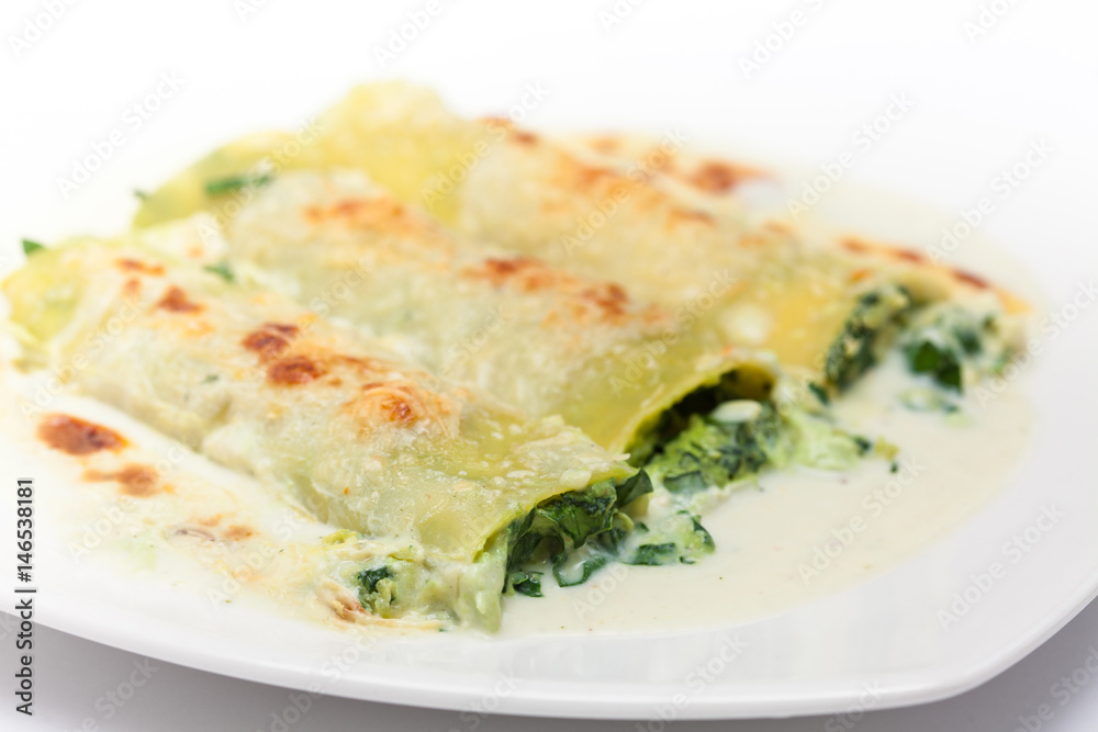 Spinach and cheese cannelloni preparation : Served spinach and cheese cannelloni on a white dish Spinach and cheese cannelloni preparation : Served spinach and cheese cannelloni on a white dish