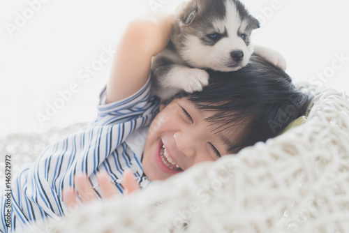 Tableau sur toile Cute asian child playing with siberian husky puppy