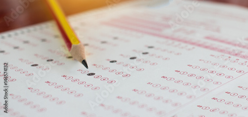 Standardized test exams form with answers bubbled in and color pencil resting on the paper test, education concept photo