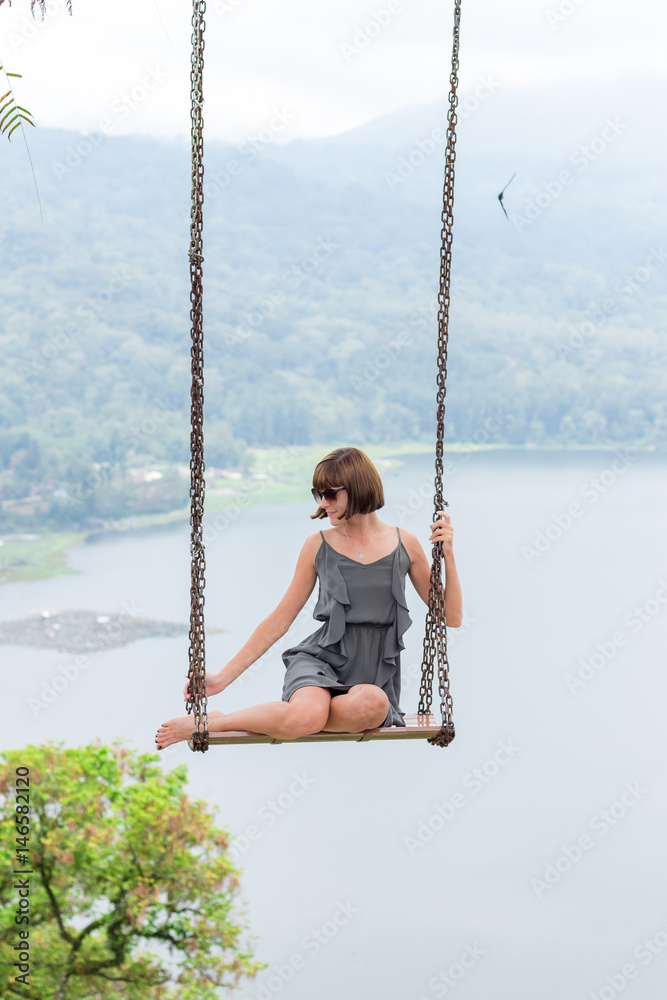 Sexy young aldy swinging over the precipice on the magic tropical Bali island, Indonesia.