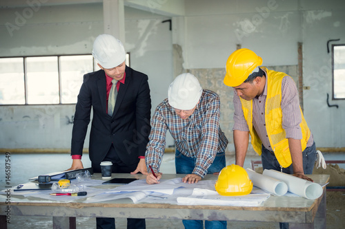 Management consulting and engineers and foreman working with blueprint and drawing on work table for management business plan and construction site project.