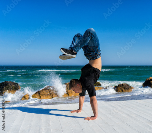 Young Athlete walkimg on hands on the beach. Street workout. break dancer man doing handstand photo