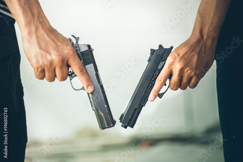 Two Robbers holding a gun at abandoned building. Low key photo and selective focus. criminality concept.