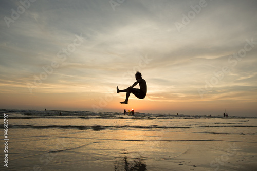 silhouette happiness man jump during sunset or sunrise while on holiday at the beach.