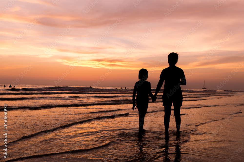 silhouette of mother and child walking on the tropical beach sunset background silhouette of mother and child walking on the tropical beach sunset background