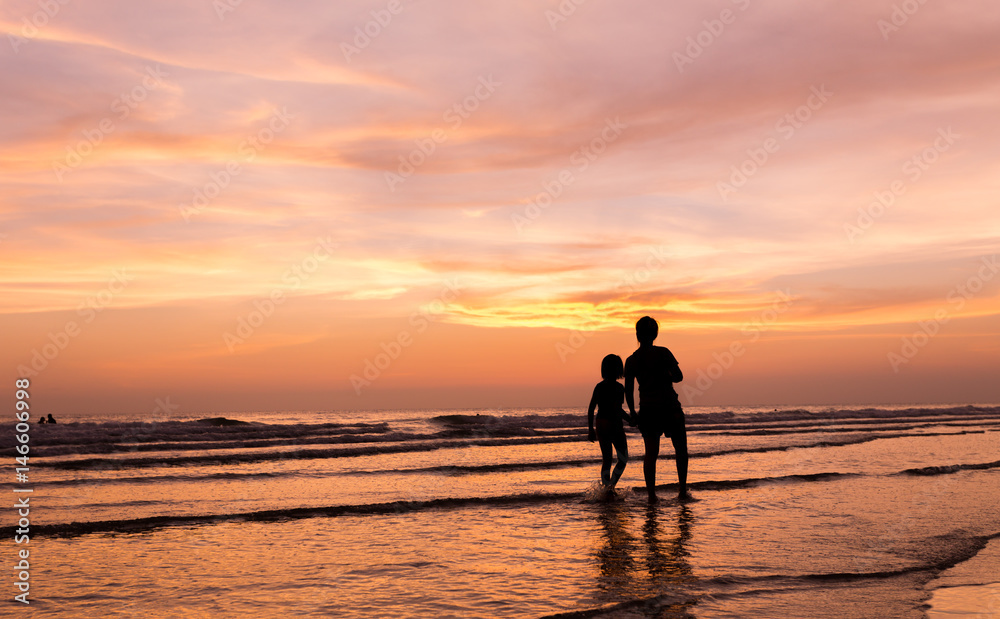 silhouette of mother and child  walking on the tropical beach  sunset background