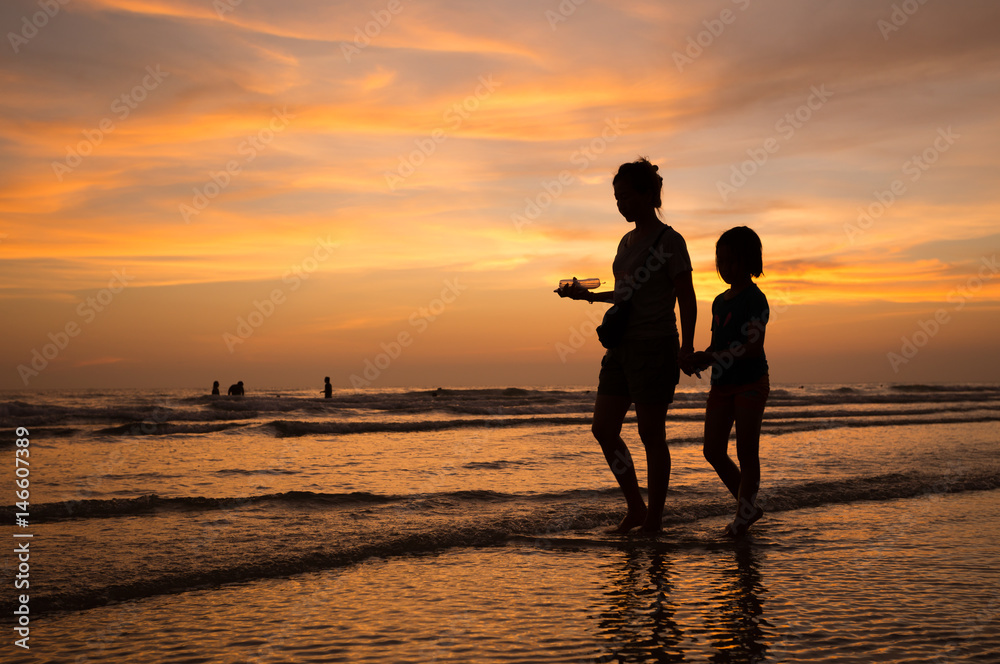 silhouette of mother and child  walking on the tropical beach  sunset background