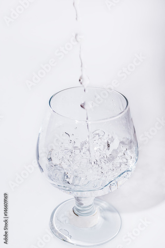 Water pouring into the glass over white background