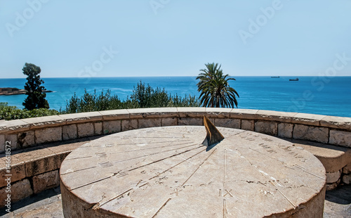 Roman sundial vintage large round stone on a hill above the sea in Sunny cloudless day horizontally