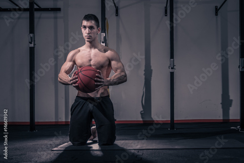 one young man, bodybuilder kneeling ball