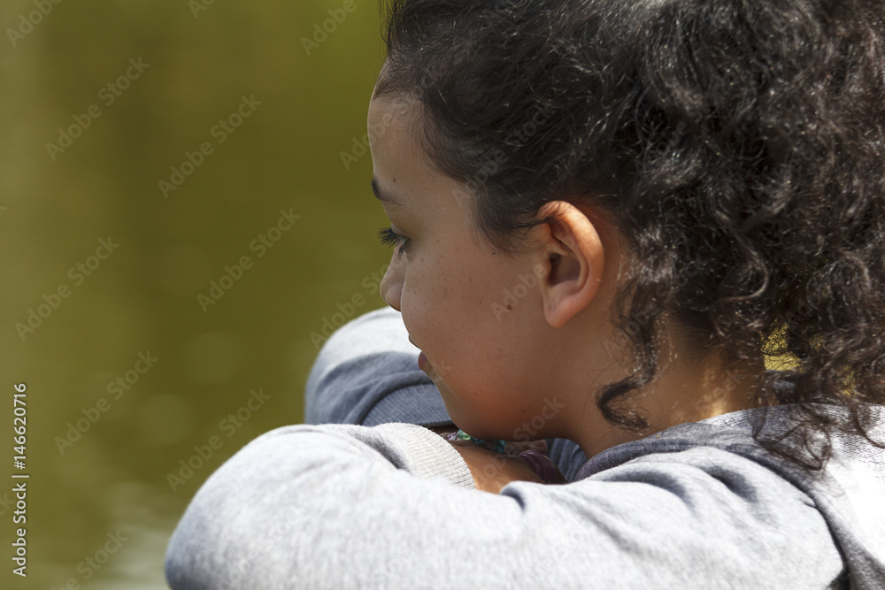Niña morena rizosa pensativa en el parque Niña morena rizosa pensativa en el parque
