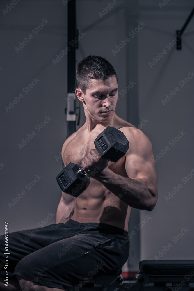 one young man, bodybuilder training dumbbell biceps