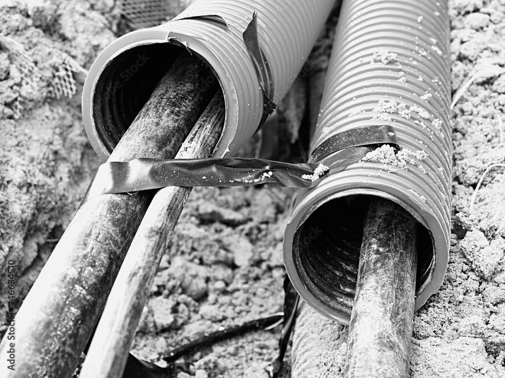 Excavation of trench with black cables in protective HDPE tube. Lines