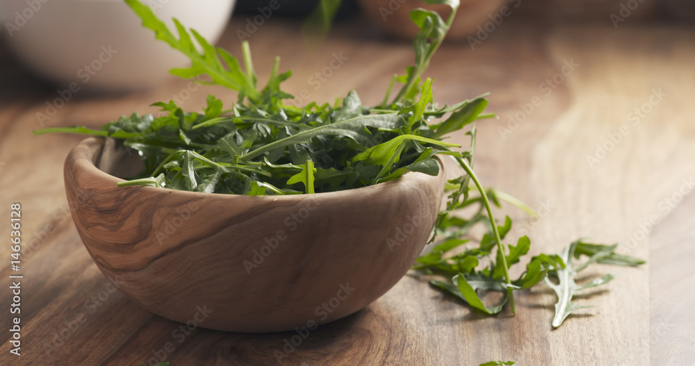 washed arugula leaves falling into the bowl on wooden table, 4k photo washed arugula leaves falling into the bowl on wooden table, 4k photo