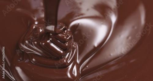 premium dark melted chocolate being poured from spoon in left part of frame from above toned, 4k photo