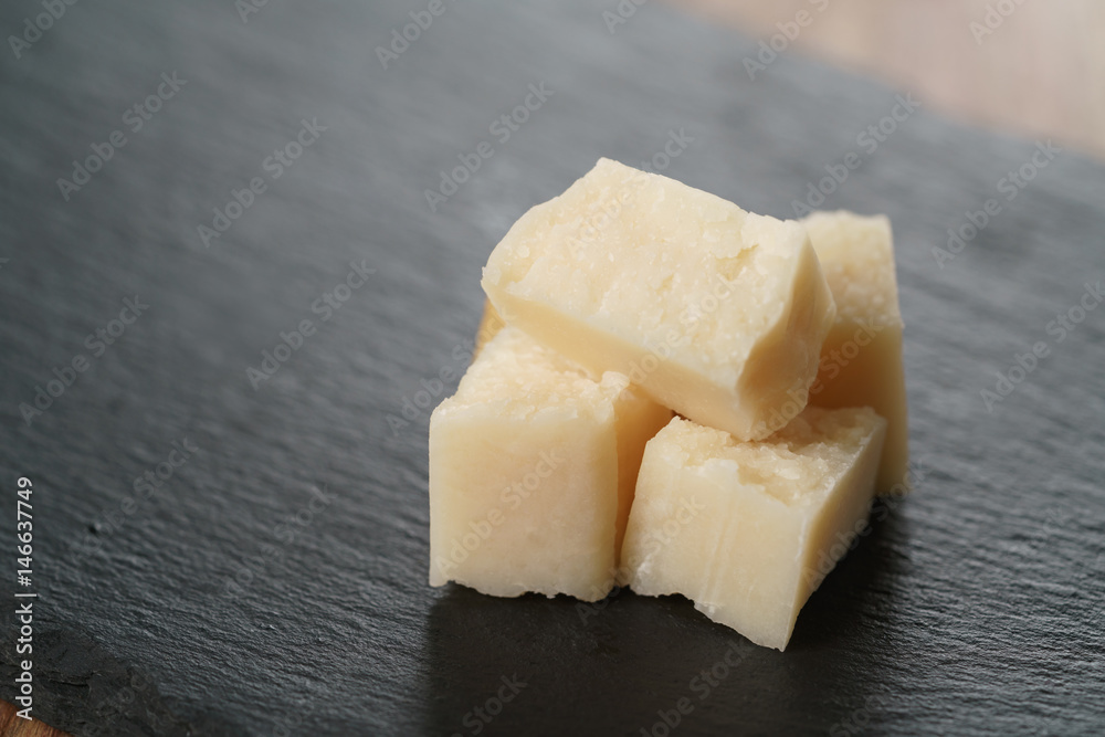 pieces of hard parmesan cheese on slate board, closeup photo