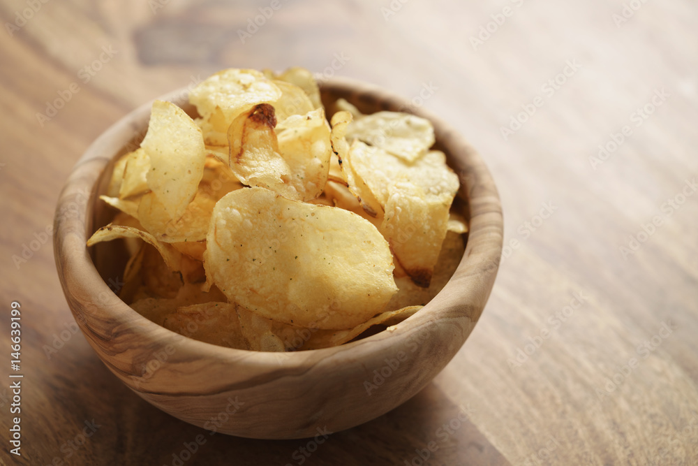 potato chips with herbs in wood bowl on rustic table potato chips with herbs in wood bowl on rustic table