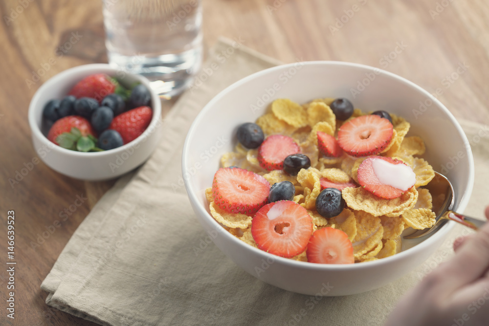 female teen girl hand eats healthy breakfast with corn flakes and berries, slightly toned photo female teen girl hand eats healthy breakfast with corn flakes and berries, slightly toned photo