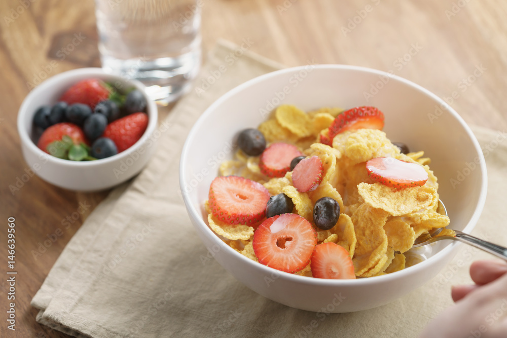 female teen girl hand eats healthy breakfast with corn flakes and berries, slightly toned photo