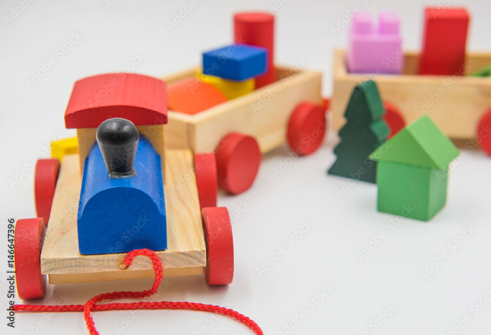 Obraz premium Zabawkowy pociąg wykonany z kolorowego drewna na białym tle.
