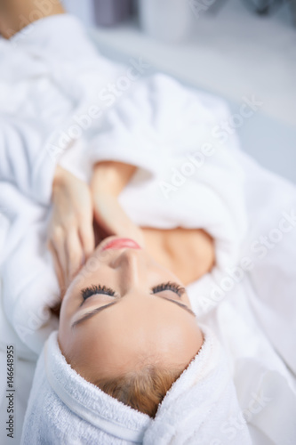 beautiful young woman wearing a white bathrobe, with a towel on her head in bed at home