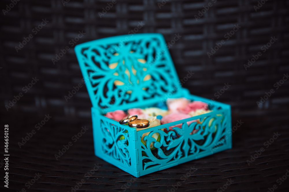 Obraz premium Wedding gold rings in a blue wooden box on the dark background. Concept of love