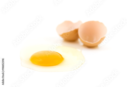 raw fresh egg on white surface, cracked eggshell on background, blurred