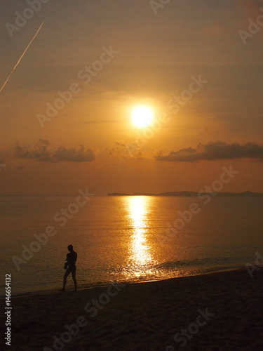 Ａ men carry a baby in front walking in the dusk at Ko Samui beach,Thailand © Justin Chen